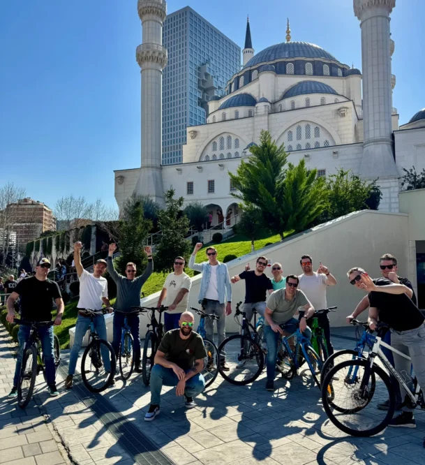 large group of men and on their self guided bike tour in front of the mosque of namazgad in tirana