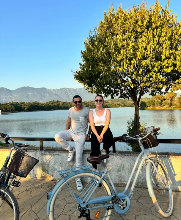 bike tour couple posing in the grand park of tirana with the lake and mountains in the backround
